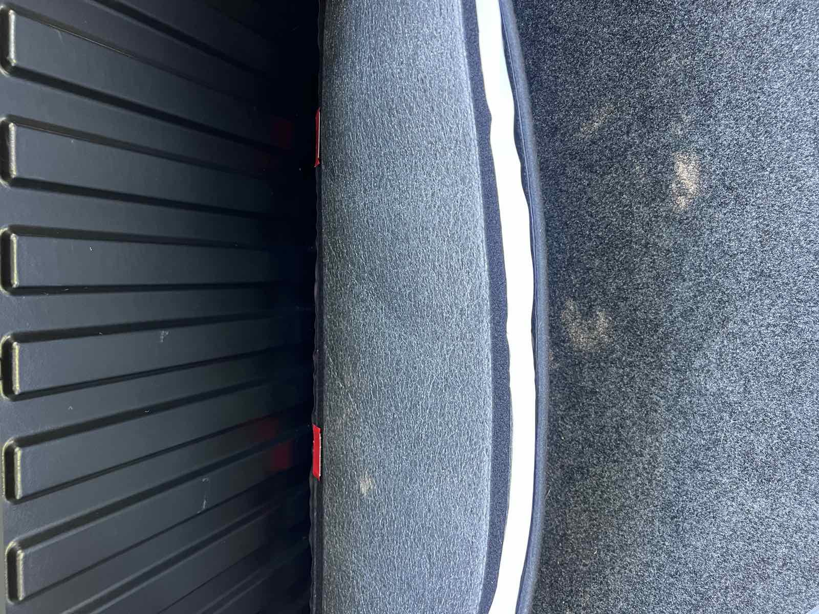 Interior view of a Tacoma tailgate with the bed liner's tailgate section fitted, showing the white velcro seam where the tailgate panel meets the bed floor section.