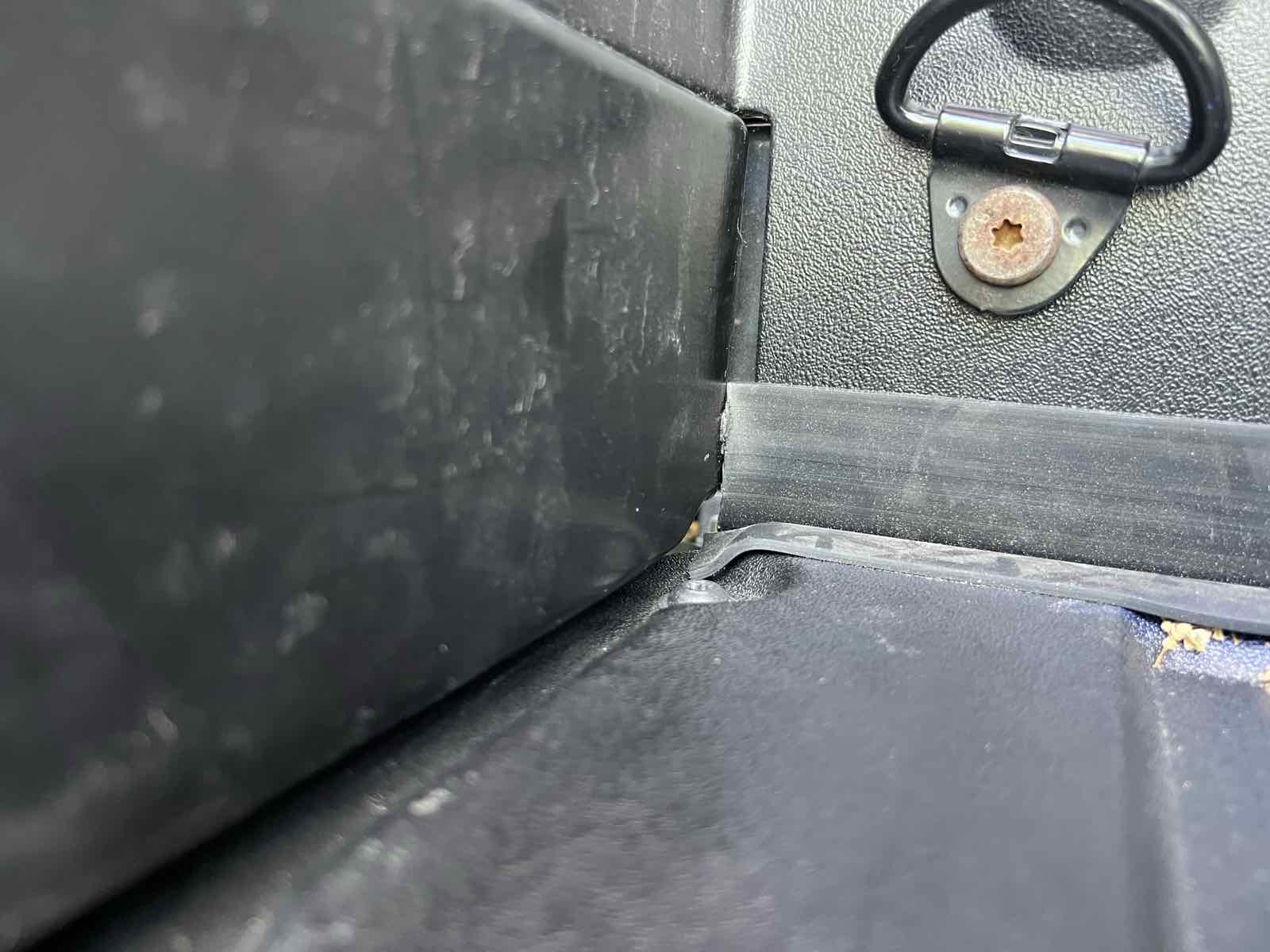 View from inside a Tacoma bed with the tailgate shut and only the ROK Block gap cover installed, showing daylight visible through the open corner where the tailgate meets the bed sidewall.