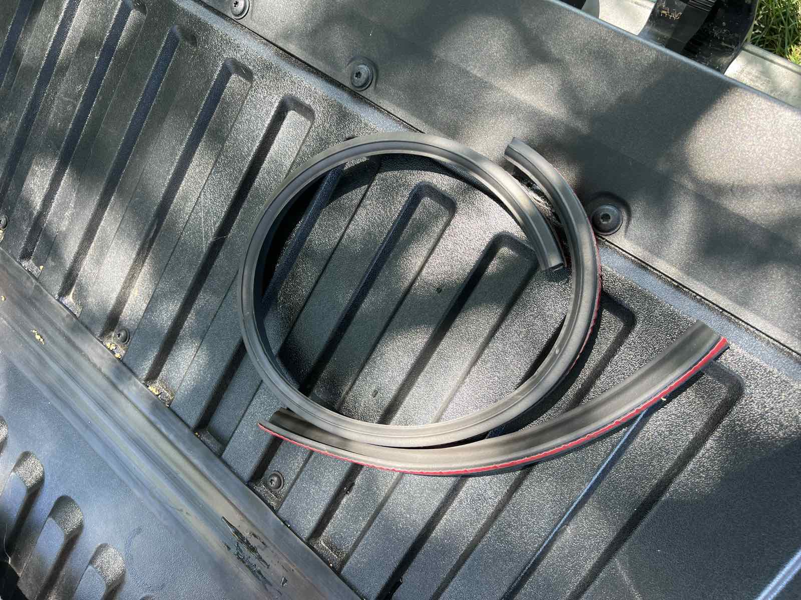 A length of black ESI taper seal extrusion with red adhesive backing tape, laid out on the back of a vehicle ready for installation.